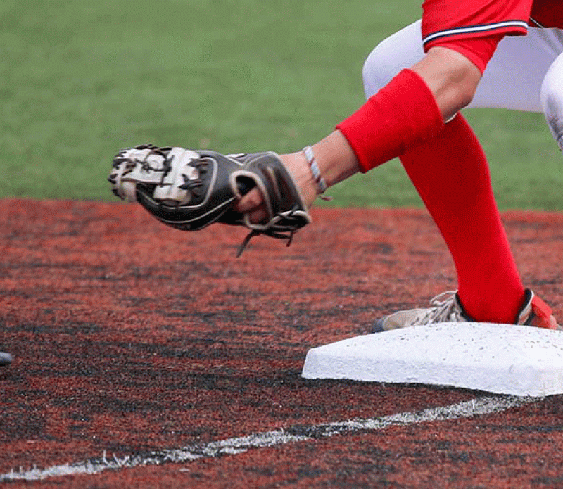 Baseball player stretching to field a throw at the base during a game