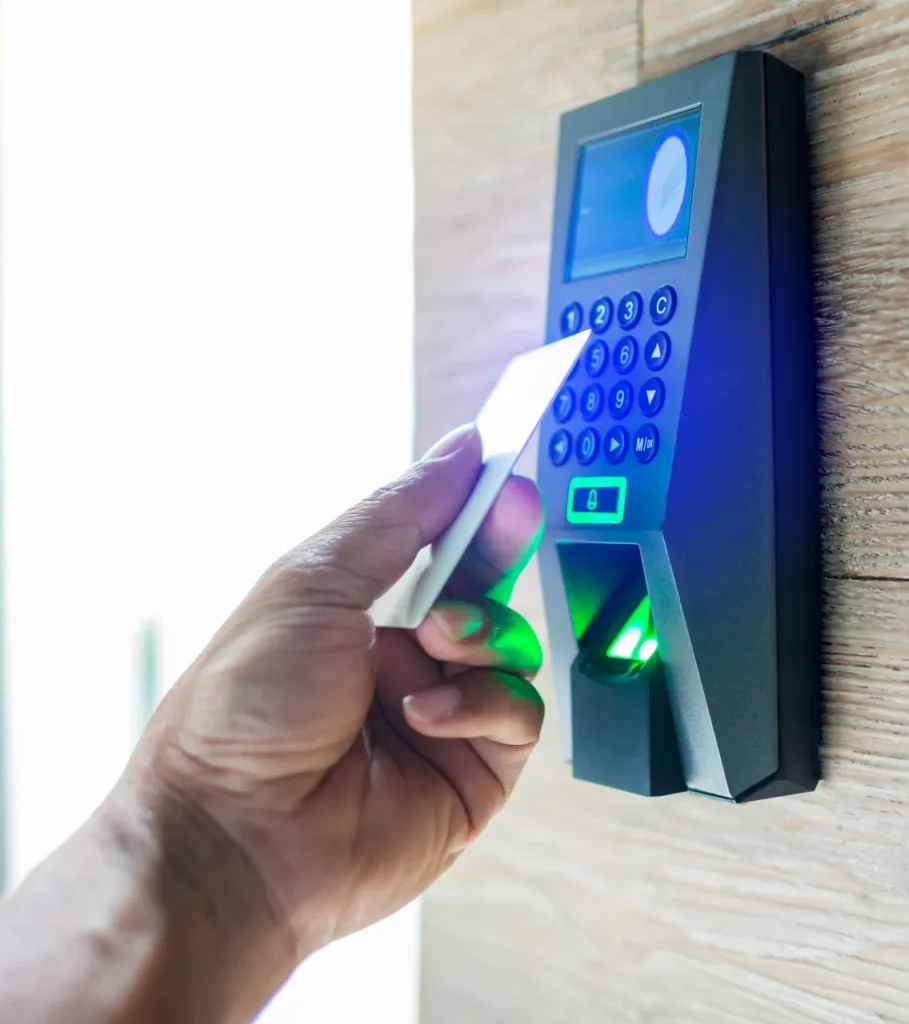 Employee holding a key card to a wall-mounted access control keypad with fingerprint scanner