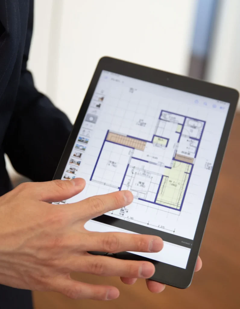 Surveyor reviewing a building floor plan on a tablet during a site walkthrough