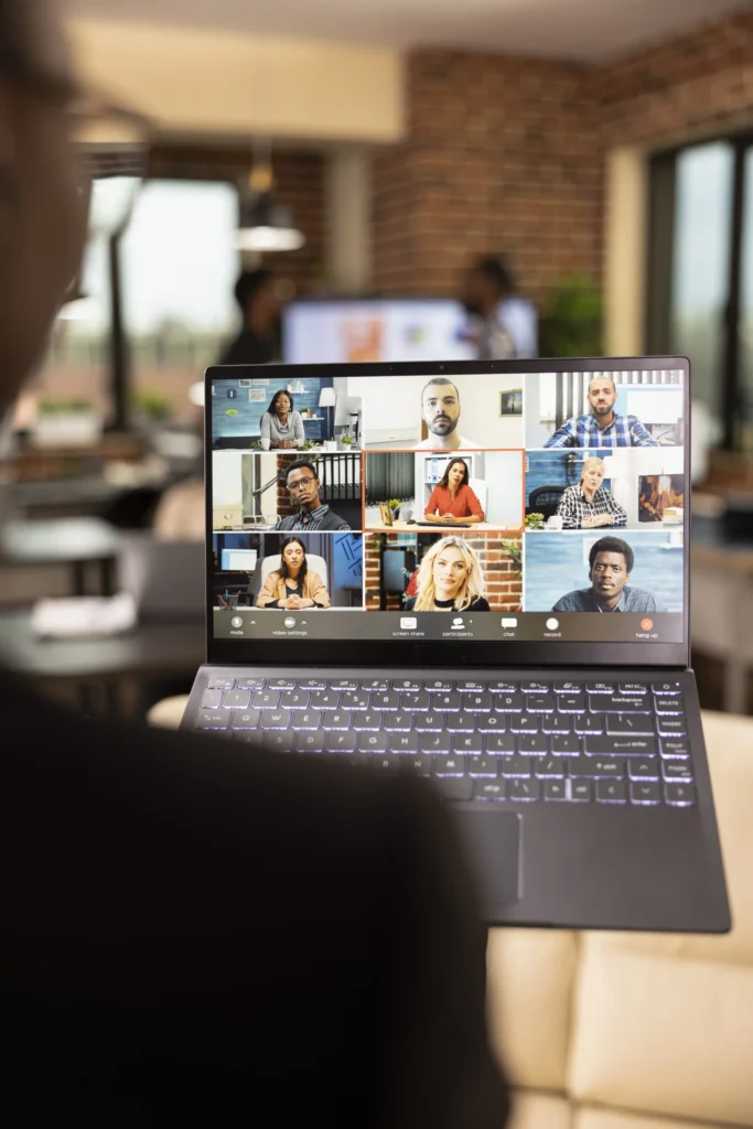 Employee joining a nine-person video conference call on a laptop in an office